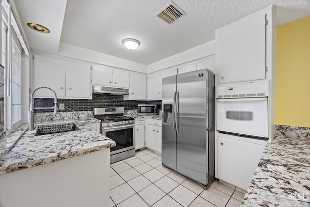 kitchen with visible vents, under cabinet range hood, a sink, stainless steel appliances, and light tile patterned floors