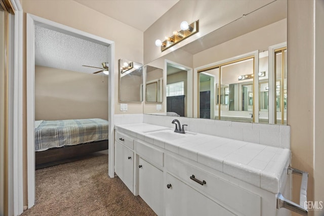 ensuite bathroom with ensuite bath, ceiling fan, vanity, and a textured ceiling