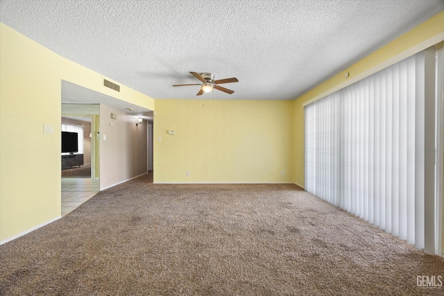 empty room with visible vents, carpet floors, a textured ceiling, and a ceiling fan