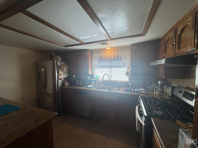 4105 Thatch Ave, Bakersfield, CA 93313 - kitchen with appliances with stainless steel finishes, under cabinet range hood, a sink, dark countertops, and dark tile patterned floors