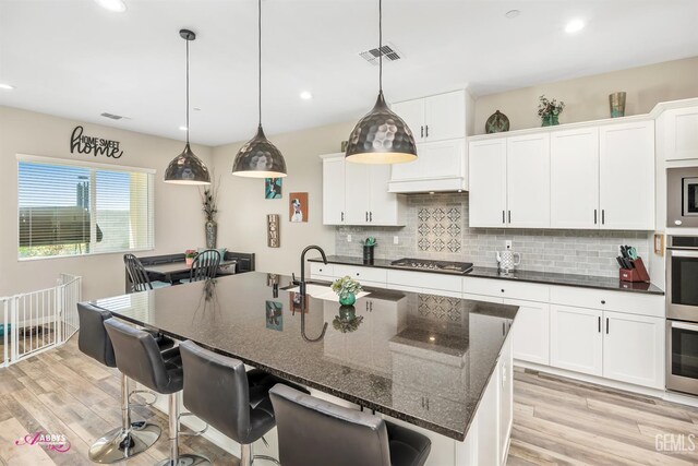 802 Barre Ct, Bakersfield, CA 93314 - kitchen featuring stainless steel gas cooktop, backsplash, light wood-style floors, a breakfast bar area, and recessed lighting
