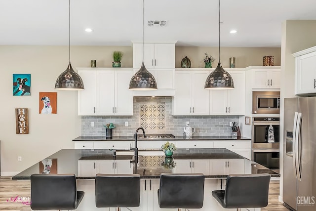 802 Barre Ct, Bakersfield, CA 93314 - kitchen featuring appliances with stainless steel finishes, decorative backsplash, dark countertops, a kitchen breakfast bar, and recessed lighting