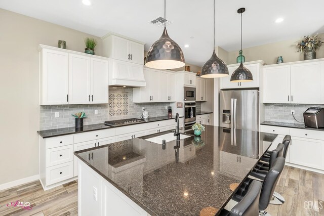 802 Barre Ct, Bakersfield, CA 93314 - kitchen featuring appliances with stainless steel finishes, tasteful backsplash, a breakfast bar area, light wood finished floors, and recessed lighting