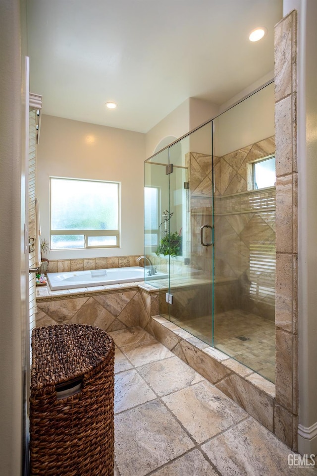 bathroom featuring a garden tub, a stall shower, stone tile floors, and a wealth of natural light