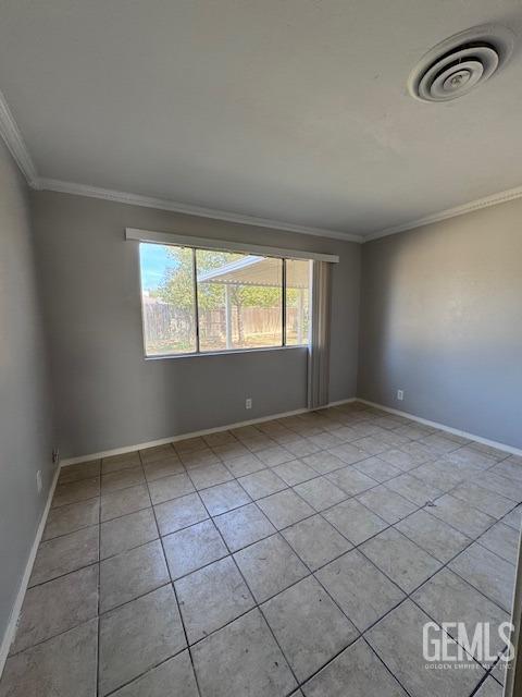 tiled empty room featuring crown molding