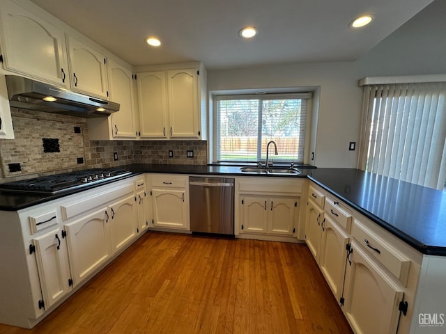 kitchen with white cabinets, sink, light hardwood / wood-style flooring, decorative backsplash, and appliances with stainless steel finishes