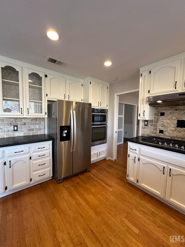 kitchen featuring tasteful backsplash, white cabinets, stainless steel appliances, and light hardwood / wood-style floors