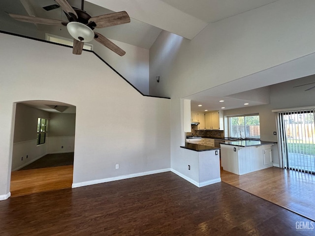 kitchen with ceiling fan, dark hardwood / wood-style floors, kitchen peninsula, decorative backsplash, and white cabinets