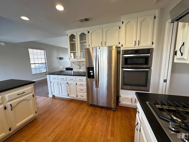 kitchen featuring white cabinetry, light hardwood / wood-style flooring, exhaust hood, and appliances with stainless steel finishes