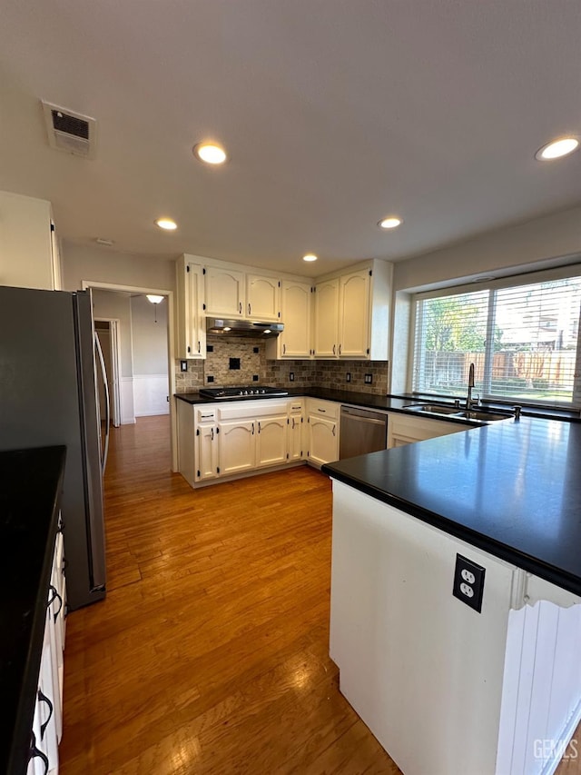 kitchen featuring white cabinets, light hardwood / wood-style floors, appliances with stainless steel finishes, and tasteful backsplash