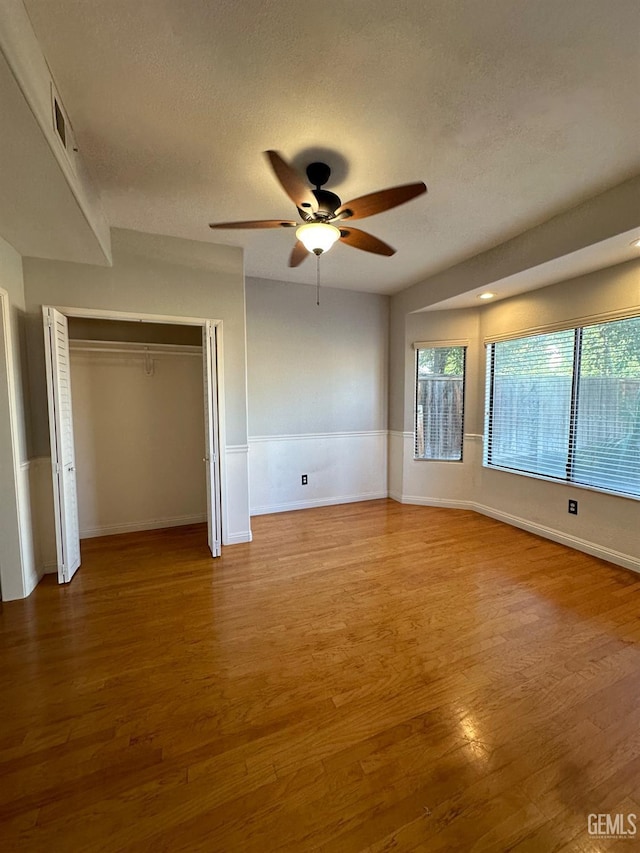 unfurnished bedroom featuring ceiling fan, wood-type flooring, a textured ceiling, and a closet