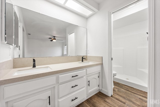 full bath with a sink, toilet, wood finished floors, and ceiling fan