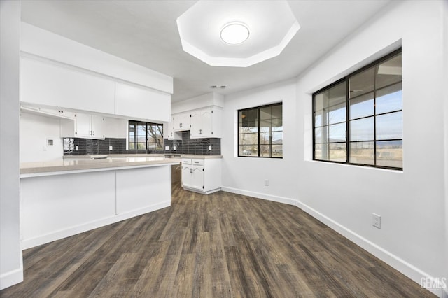 kitchen with backsplash, baseboards, light countertops, white cabinets, and dark wood-style flooring