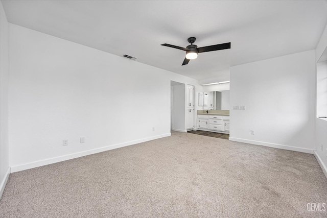 interior space featuring visible vents, baseboards, carpet floors, ensuite bath, and a ceiling fan