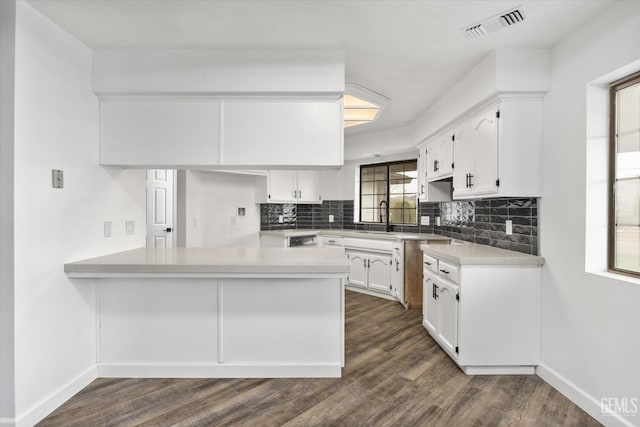 kitchen with visible vents, backsplash, dark wood finished floors, white cabinetry, and a peninsula