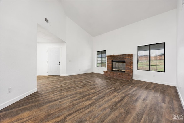 unfurnished living room with visible vents, high vaulted ceiling, wood finished floors, a fireplace, and baseboards