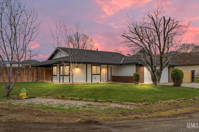 view of front of home with an attached garage, a front lawn, and fence