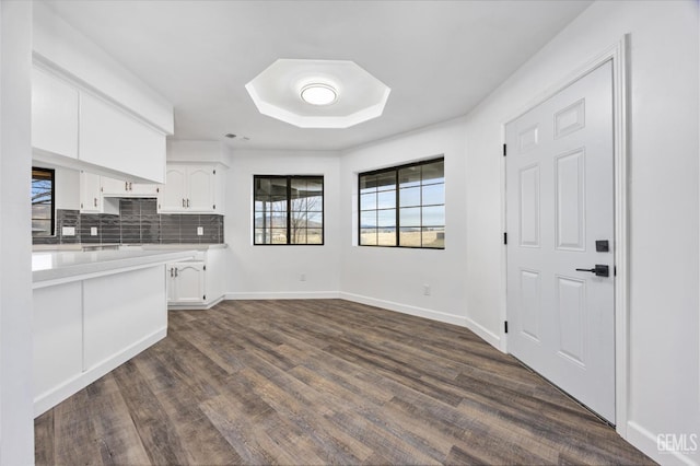 kitchen with baseboards, dark wood-style flooring, decorative backsplash, light countertops, and white cabinets