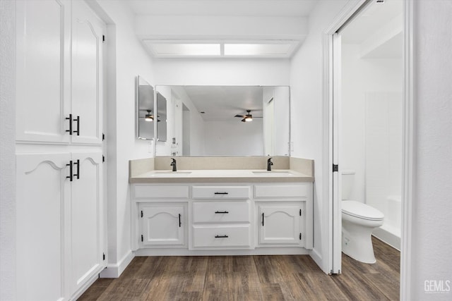 bathroom with a sink, toilet, wood finished floors, and ceiling fan