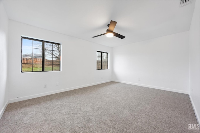 spare room with a ceiling fan, visible vents, carpet floors, and baseboards