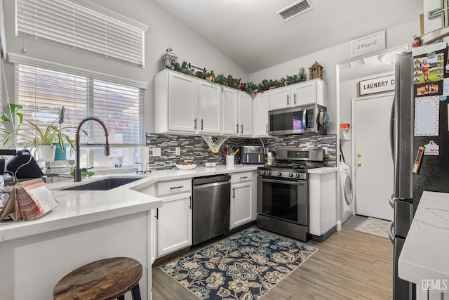 5000 Rogue Water Ct, Bakersfield, CA 93313 - kitchen featuring appliances with stainless steel finishes, washer / dryer, tasteful backsplash, light countertops, and white cabinets