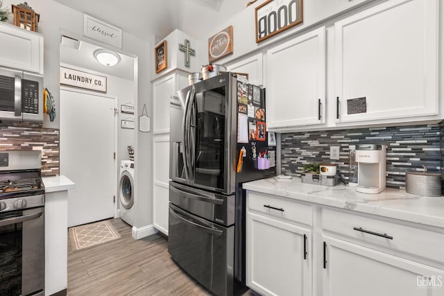 5000 Rogue Water Ct, Bakersfield, CA 93313 - kitchen featuring appliances with stainless steel finishes, washer / clothes dryer, white cabinetry, tasteful backsplash, and light wood-type flooring