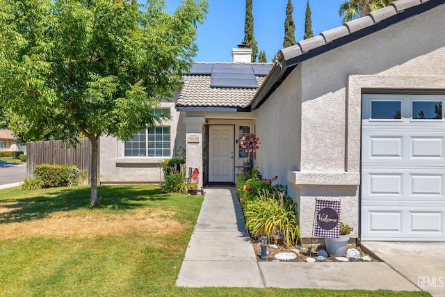 5000 Rogue Water Ct, Bakersfield, CA 93313 - view of exterior entry with stucco siding, roof mounted solar panels, a lawn, a tile roof, and a garage