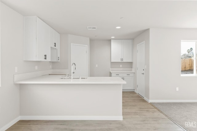 618 Poinsettia St, Bakersfield, CA 93307 - kitchen with a peninsula, light countertops, white cabinetry, light wood-style floors, and recessed lighting