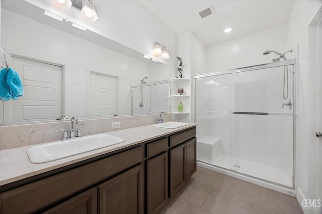 bathroom featuring tile patterned floors, visible vents, a stall shower, and a sink