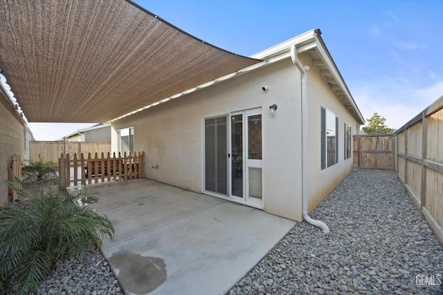 back of property with a fenced backyard, stucco siding, and a patio area