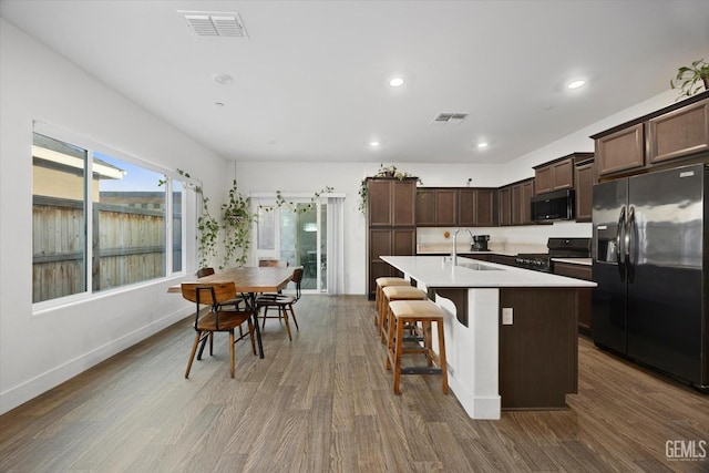 kitchen featuring visible vents, black gas stove, refrigerator with ice dispenser, and a sink