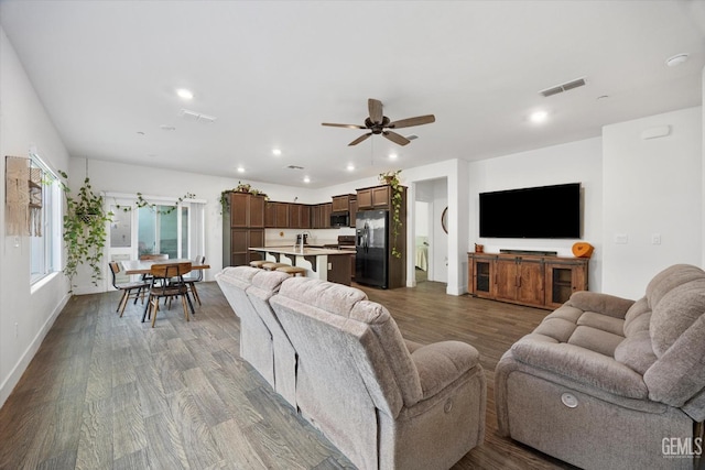 living room with dark wood-type flooring, visible vents, and recessed lighting