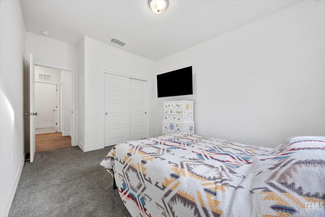 carpeted bedroom with visible vents and a closet