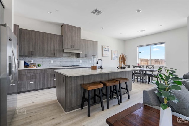 1215 Brookline Ln, Bakersfield, CA 93314 - kitchen featuring stainless steel fridge, a breakfast bar area, light wood-style floors, modern cabinets, and recessed lighting