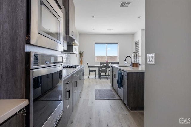 1215 Brookline Ln, Bakersfield, CA 93314 - kitchen with appliances with stainless steel finishes, a sink, light wood-style floors, light countertops, and backsplash