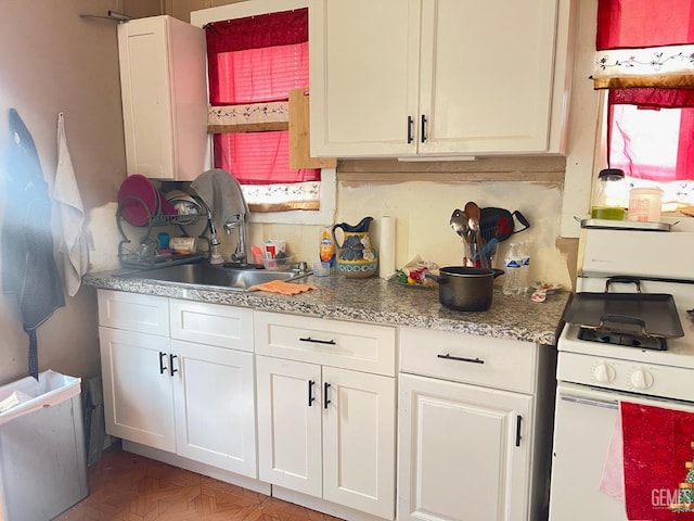 kitchen featuring sink, tasteful backsplash, parquet floors, white gas range, and white cabinets