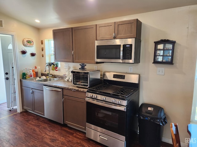 kitchen with appliances with stainless steel finishes, dark hardwood / wood-style floors, and sink