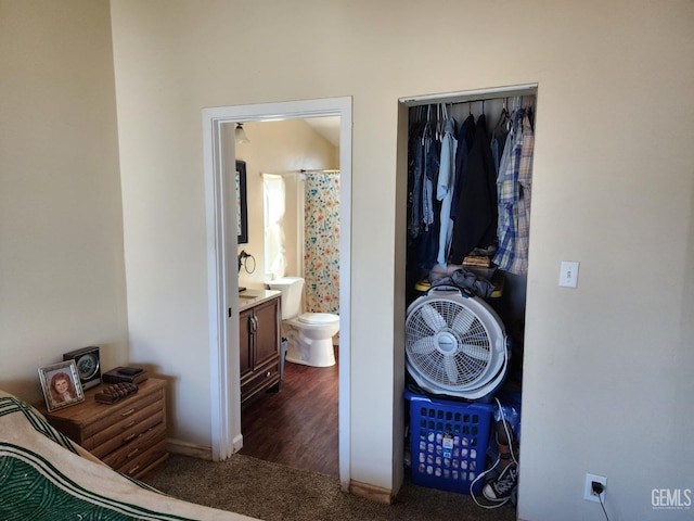 bedroom featuring connected bathroom, dark carpet, and a closet