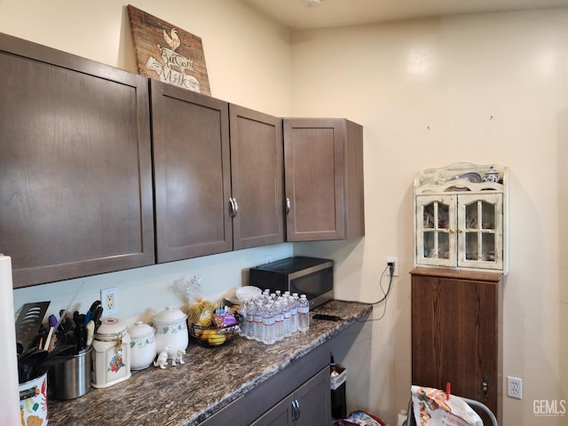 kitchen with dark brown cabinetry and dark stone countertops