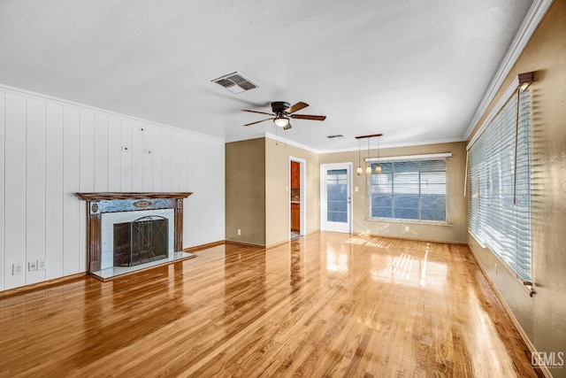 unfurnished living room with ceiling fan, light wood-type flooring, and ornamental molding