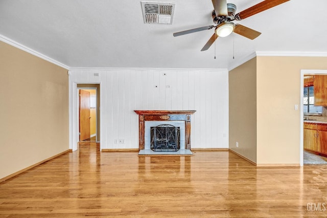 unfurnished living room featuring ceiling fan, ornamental molding, and light hardwood / wood-style flooring