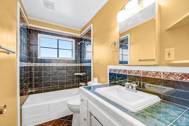 full bathroom featuring tiled shower / bath combo, tile patterned flooring, toilet, vanity, and tile walls