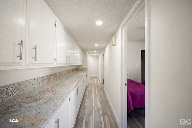 1109 Bell Ave, Taft, CA 93268 - kitchen featuring a textured ceiling, light wood-type flooring, white cabinets, baseboards, and recessed lighting
