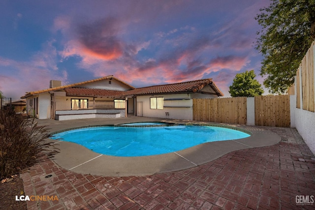 1109 Bell Ave, Taft, CA 93268 - pool at dusk with a fenced backyard, a patio, and a pool with connected hot tub
