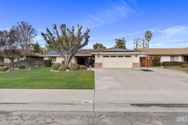 ranch-style house featuring a garage, a front yard, and solar panels