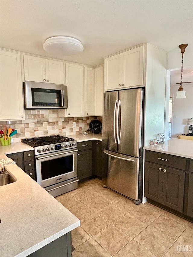 kitchen featuring decorative light fixtures, white cabinets, decorative backsplash, and appliances with stainless steel finishes