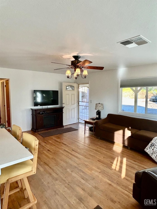 living room featuring ceiling fan, a textured ceiling, and light hardwood / wood-style flooring