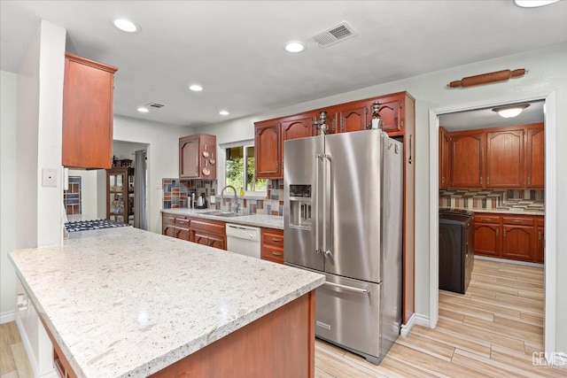 253 E Mckee Rd, Bakersfield, CA 93307 - kitchen featuring stainless steel appliances, washer / dryer, a peninsula, backsplash, and light wood-style floors