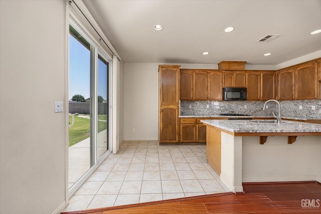9711 Boothbay Harbour Dr, Bakersfield, CA 93314 - kitchen with black microwave, brown cabinetry, decorative backsplash, baseboards, and recessed lighting