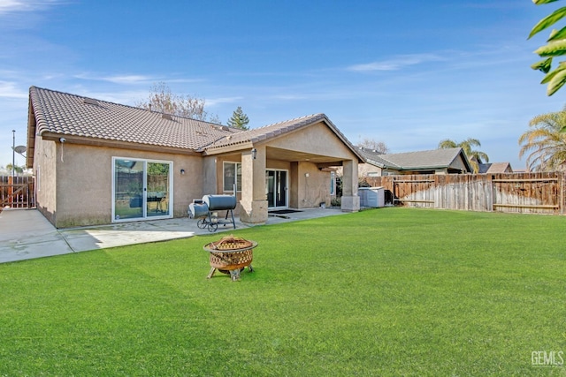 back of property with a yard, a fire pit, and a patio area